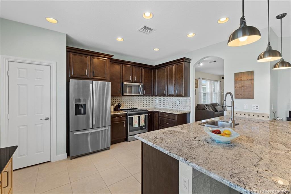 1171 Southeast Kirk Street Stuart, FL 34997 - Photo 10 of 47 a kitchen with stainless steel appliances granite countertop a sink refrigerator and cabinets