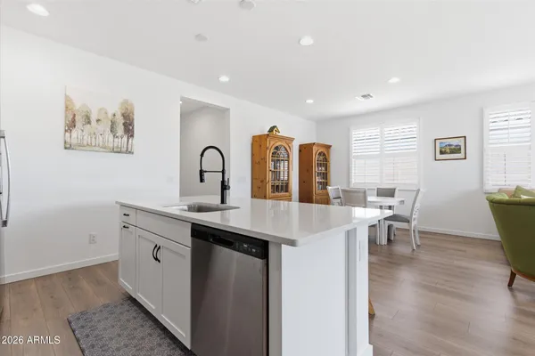 a open kitchen with stainless steel appliances granite countertop a sink a stove a dining table and chairs with wooden floor
