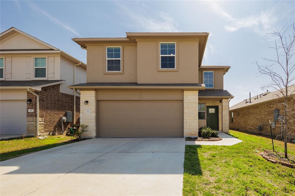 Traditional-style house with stone siding, a garage, concrete driveway, and stucco siding
