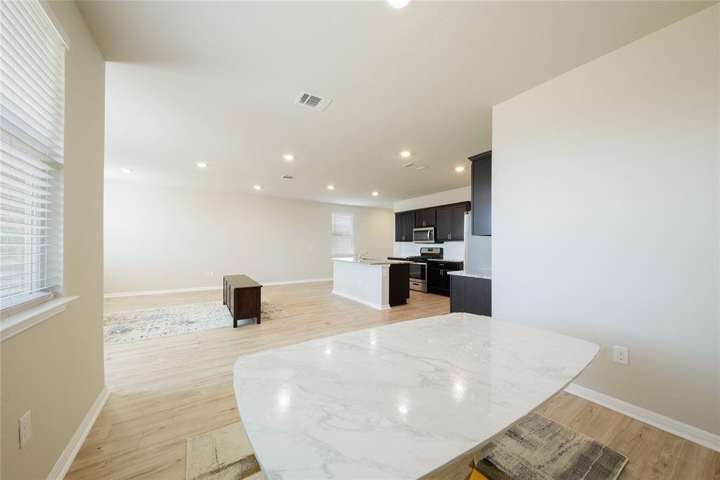 521 Otto Avenue Georgetown, TX 78626 - Photo 38 of 38 Kitchen featuring light wood finished floors, a center island with sink, open floor plan, dark cabinets, and stainless steel appliances