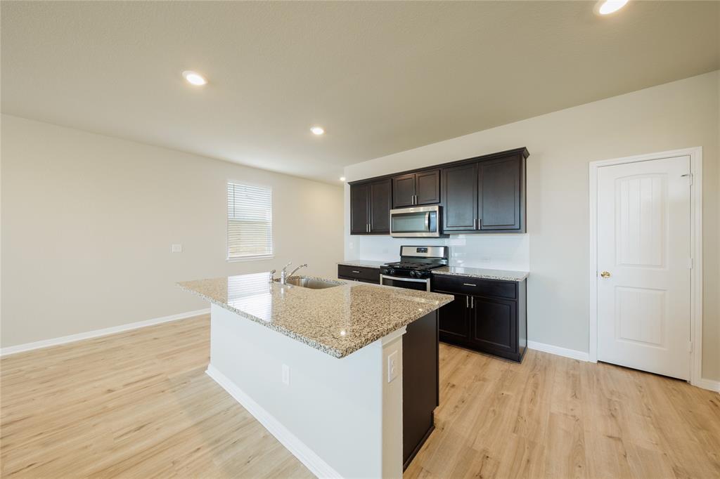 521 Otto Avenue Georgetown, TX 78626 - Photo 5 of 38 Kitchen featuring light stone countertops, an island with sink, stainless steel appliances, light wood-style flooring, and recessed lighting