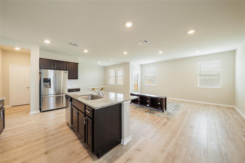 521 Otto Avenue Georgetown, TX 78626 - Photo 6 of 38 Kitchen with stainless steel appliances, dark wood finish cabinetry, light stone counters, light wood-style floors, and recessed lighting