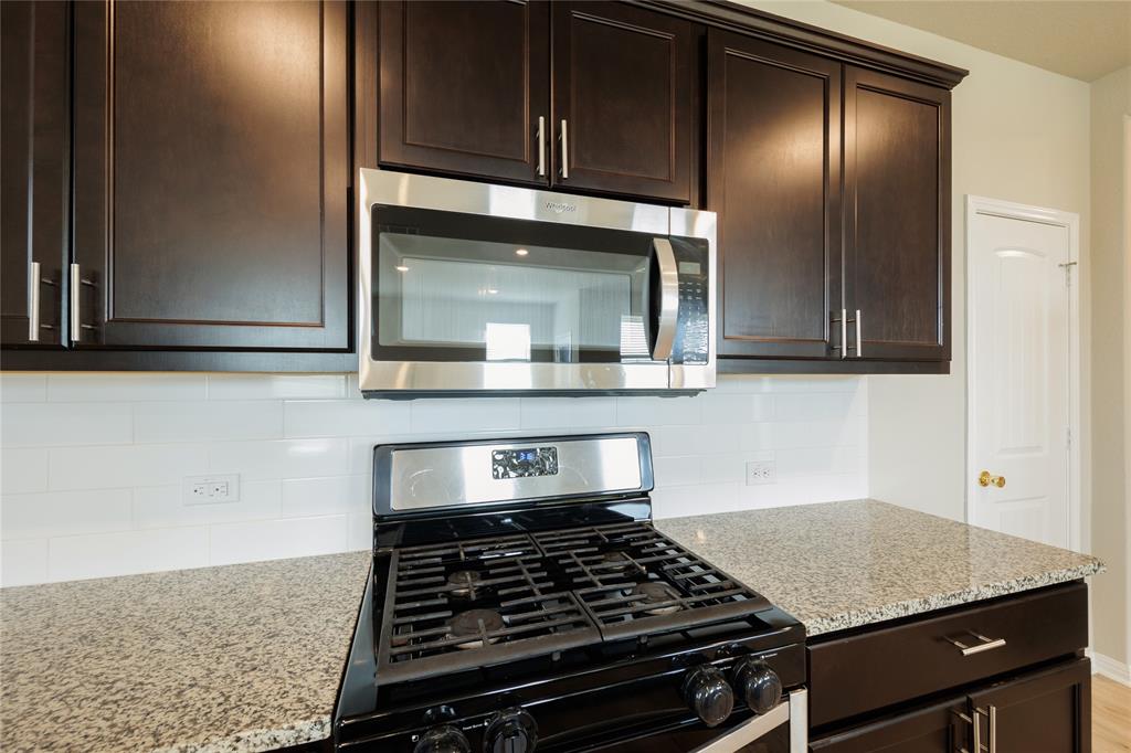 521 Otto Avenue Georgetown, TX 78626 - Photo 8 of 38 Kitchen featuring stainless steel appliances, backsplash, dark wood finish cabinetry, and light stone countertops
