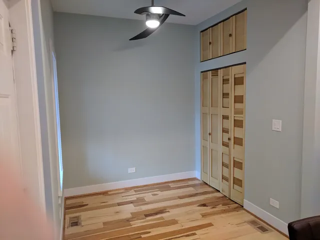 an empty room with wooden floor cabinet and windows