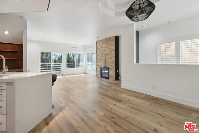 a view of an empty room with a window and kitchen view