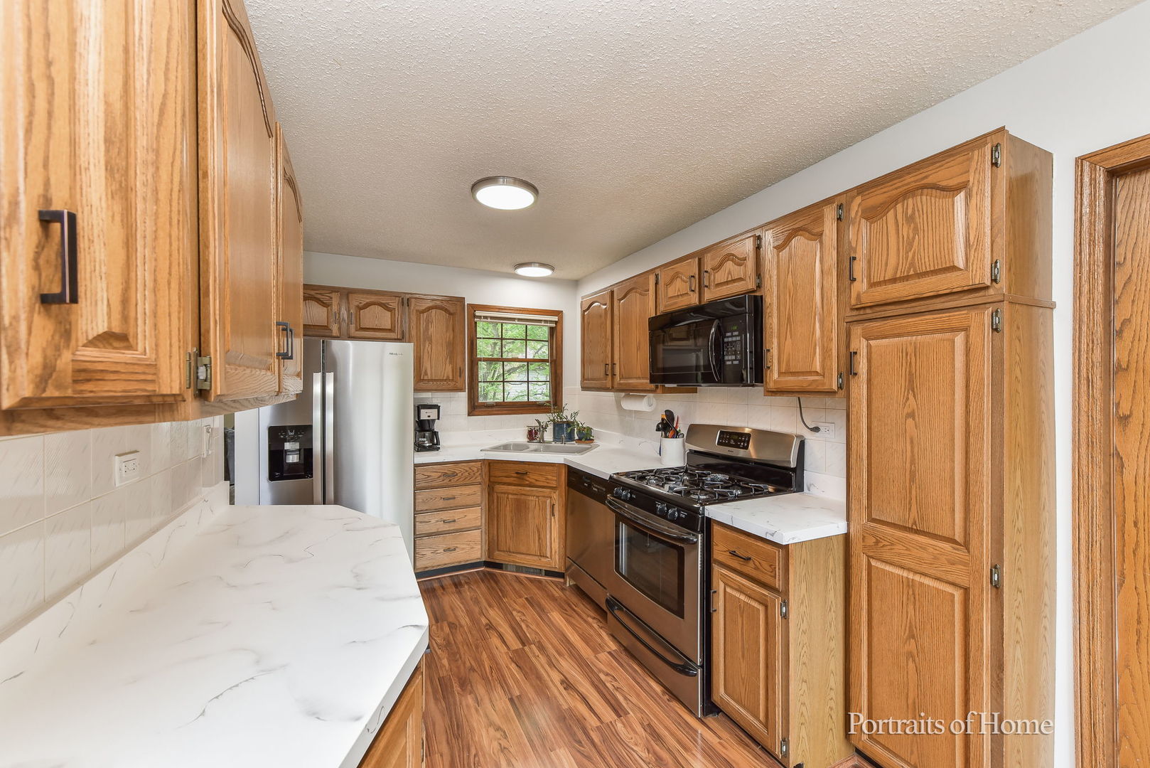 1920 Howe Lane Hanover Park, IL 60133 - Photo 12 of 25 a kitchen with stainless steel appliances granite countertop a stove top oven a sink dishwasher a dining table and chairs with wooden floor
