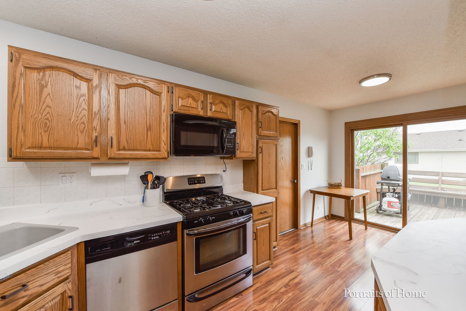 1920 Howe Lane Hanover Park, IL 60133 - Photo 13 of 25 a kitchen with stainless steel appliances granite countertop a stove top oven a sink dishwasher a dining table and chairs with wooden floor