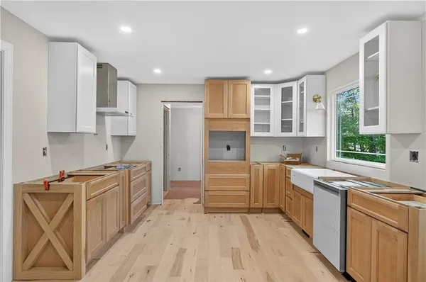 a kitchen with stainless steel appliances granite countertop a stove top oven a sink dishwasher and a refrigerator with wooden floor