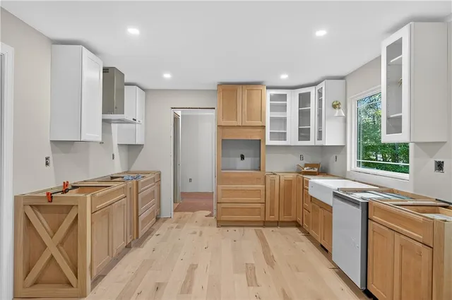 a kitchen with stainless steel appliances granite countertop a stove top oven a sink dishwasher and a refrigerator with wooden floor