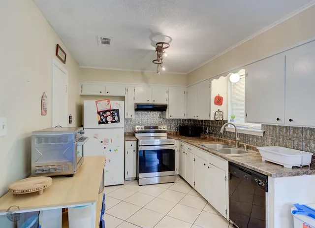 a kitchen with a sink dishwasher a stove a microwave oven and a dining table with wooden floor