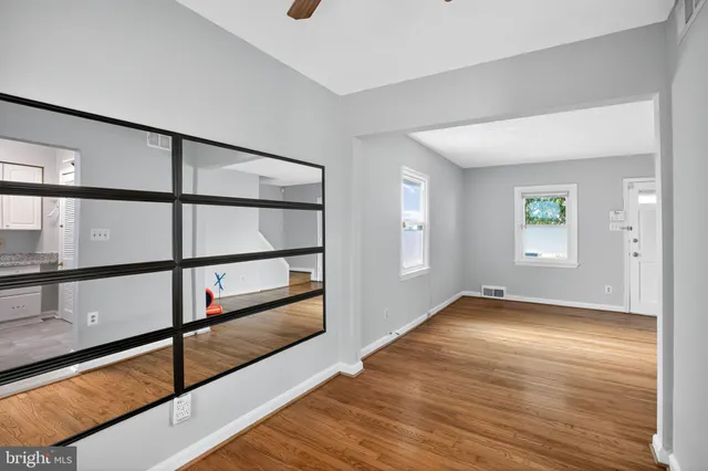 a view of empty room with wooden floor and fan