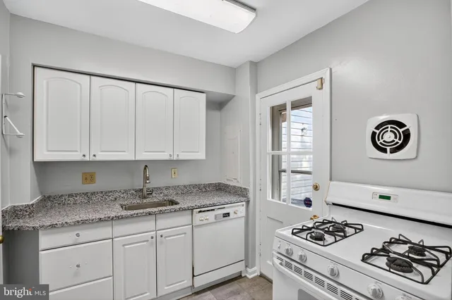 a kitchen with granite countertop cabinets and white appliances