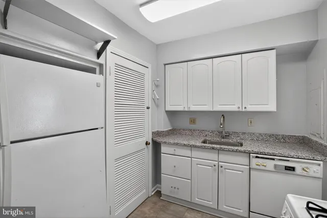 a kitchen with granite countertop a sink stove and cabinets