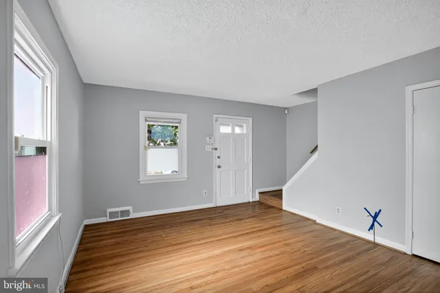 a view of an empty room with wooden floor and stairs