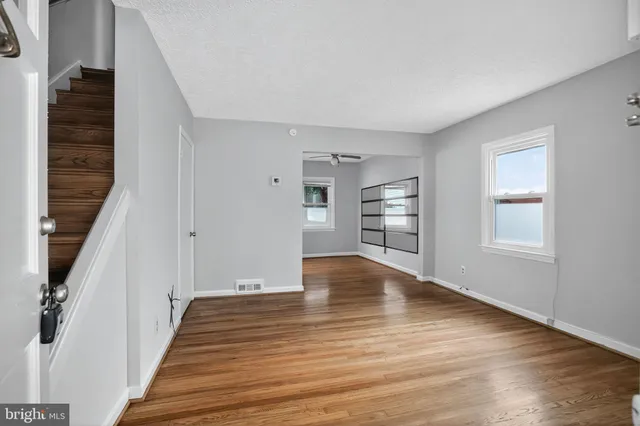 a view of an empty room with window and wooden floor