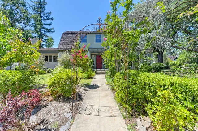 a front view of a house with plants and trees