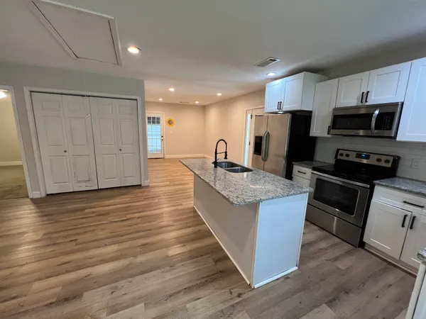 a kitchen with stainless steel appliances wooden floor and a refrigerator
