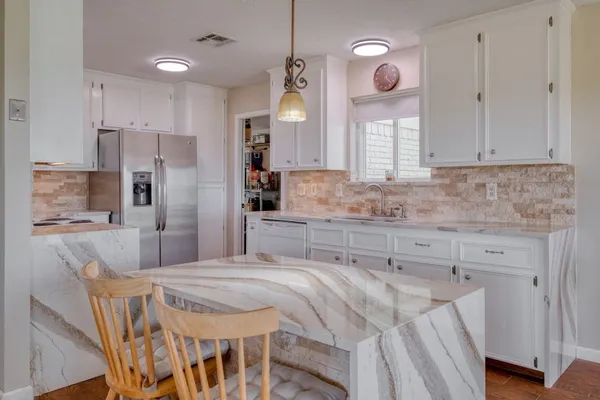 a kitchen with kitchen island granite countertop a sink cabinets and refrigerator