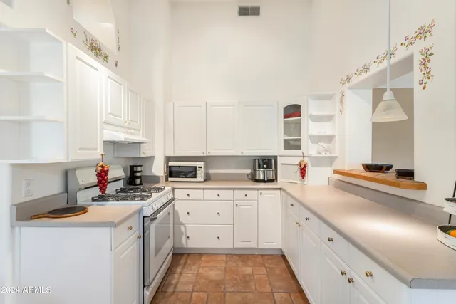 a kitchen with a sink dishwasher stove and white cabinets with wooden floor