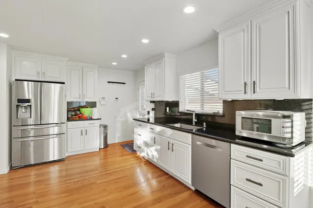 a kitchen with stainless steel appliances granite countertop a sink a stove and a wooden floors