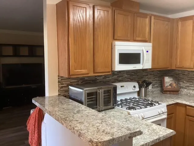 a kitchen with granite countertop a sink stove and microwave