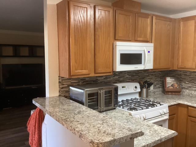 565 Peerless Way, Unit 108 Tracy, CA 95376 - Photo 7 of 15 a kitchen with granite countertop a stove a sink and a microwave