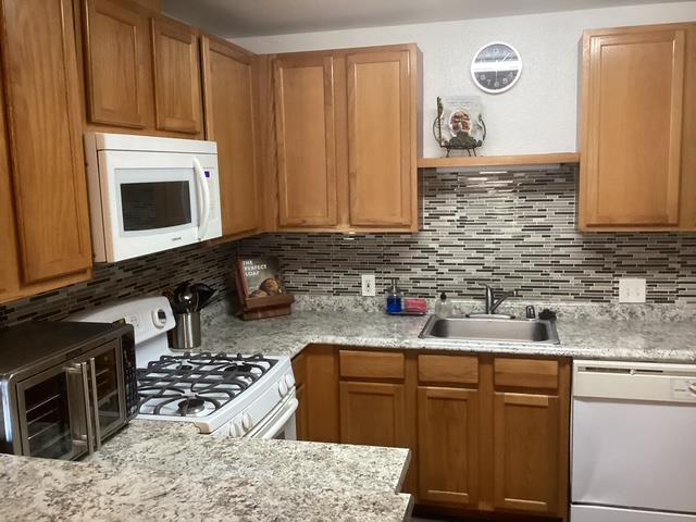 565 Peerless Way, Unit 108 Tracy, CA 95376 - Photo 8 of 15 a kitchen with granite countertop a sink stove and microwave