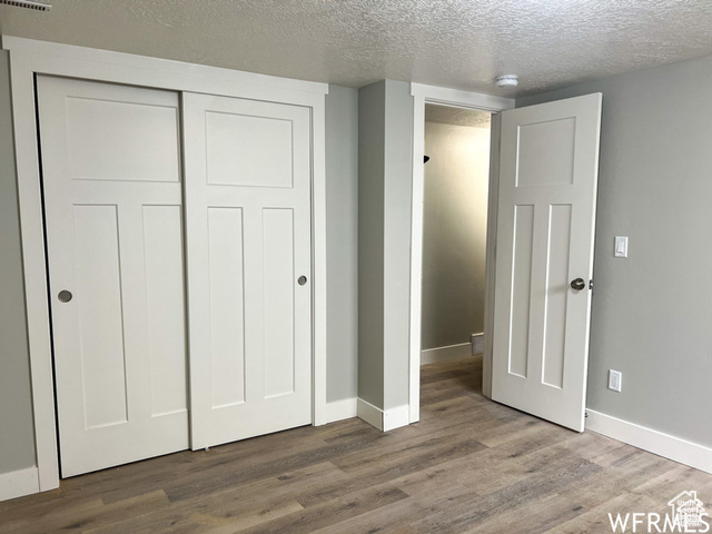 702 North 100 West Logan, UT 84321 - Photo 23 of 58 Unfurnished bedroom with baseboards, a closet, wood finished floors, and a textured ceiling
