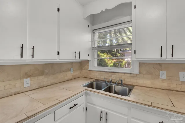 a kitchen with stainless steel appliances white cabinets a window and a sink