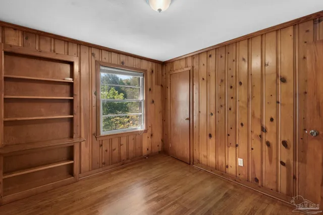 an empty room with wooden floor ceiling fan and windows