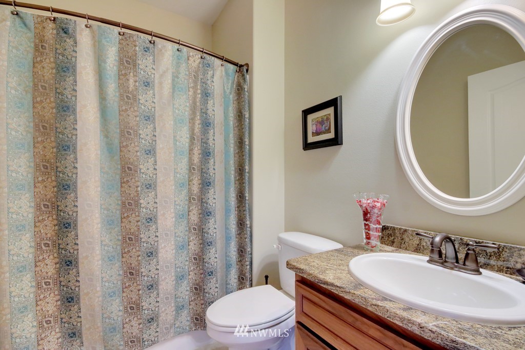 9908 Meadow Road Southwest Lakewood, WA 98499 - Photo 12 of 25 a bathroom with a granite countertop toilet a sink and a mirror