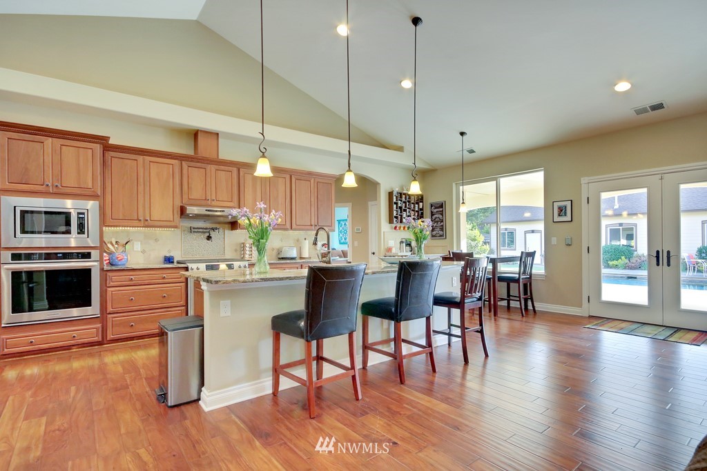 9908 Meadow Road Southwest Lakewood, WA 98499 - Photo 6 of 25 a kitchen with stainless steel appliances granite countertop a stove top oven a sink a dining table and chairs with wooden floor