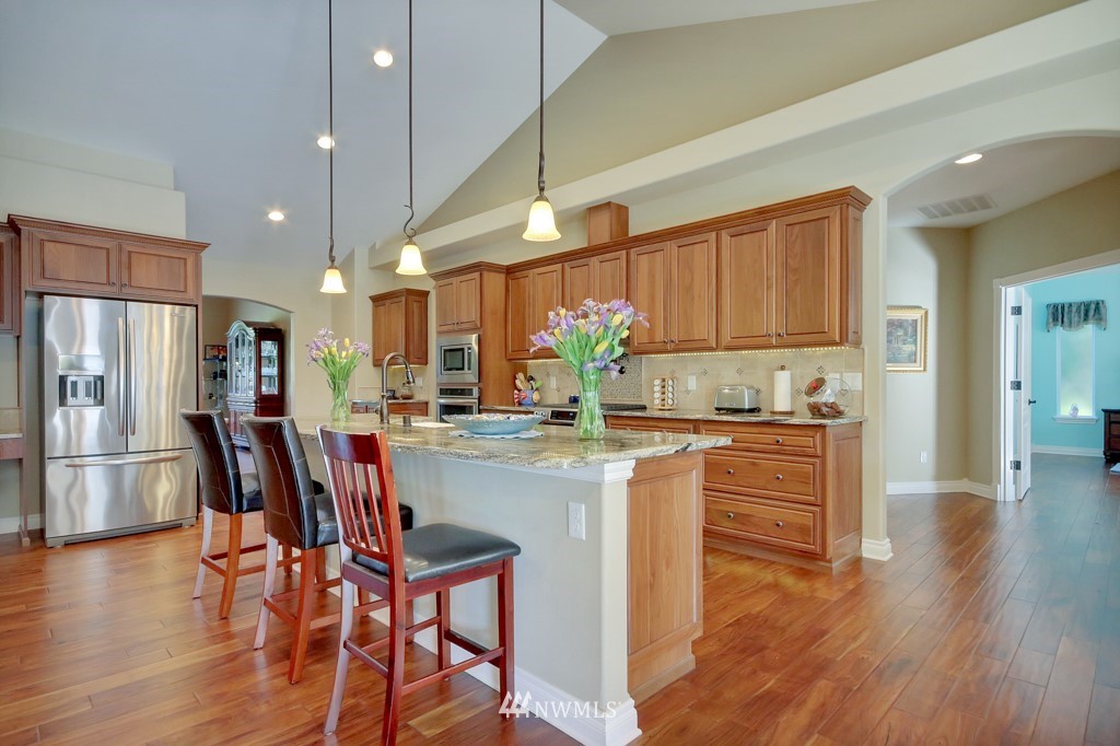 9908 Meadow Road Southwest Lakewood, WA 98499 - Photo 8 of 25 a kitchen with stainless steel appliances granite countertop wooden floor cabinets dining table and chairs