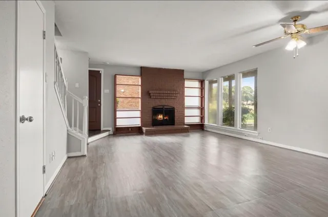 an empty room with windows fireplace and wooden floor
