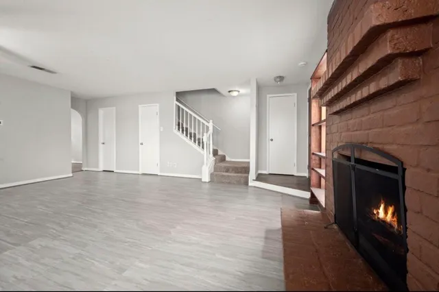 a view of an empty room with wooden floor fireplace and a window