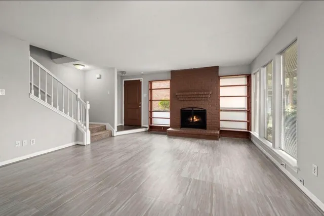 a view of an empty room with wooden floor fireplace and a window