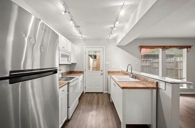 a kitchen with a refrigerator a sink and white cabinets