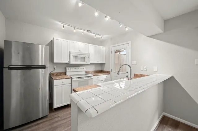 a kitchen with stainless steel appliances granite countertop a refrigerator sink and white cabinets