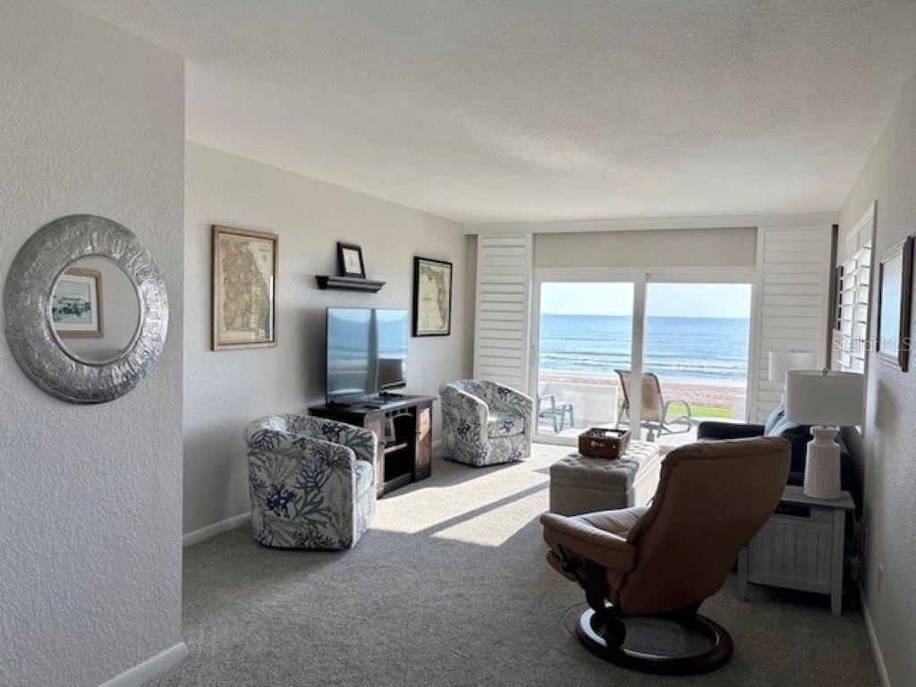 815 Ocean Shore Boulevard, Unit 13 Ormond Beach, FL 32176 - Photo 12 of 17 a living room with furniture a large window and a flat screen tv