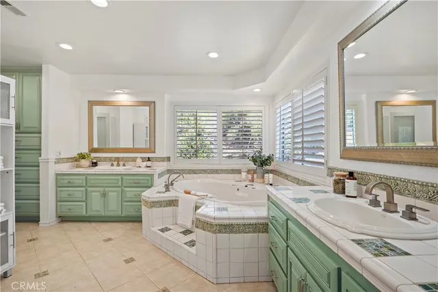 a bathroom with a granite countertop sink double vanity large mirror and a bathtub