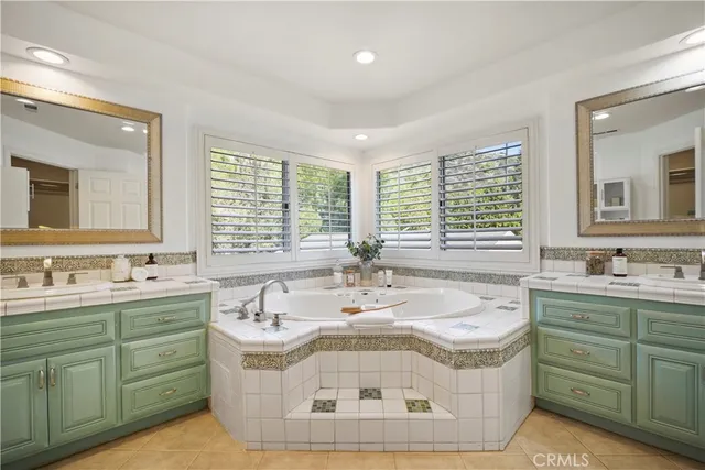 a bathroom with a granite countertop double vanity sink a mirror and a bathtub