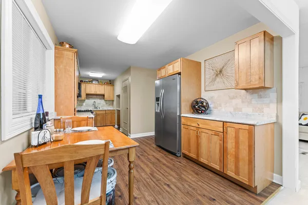 a kitchen with stainless steel appliances granite countertop a refrigerator a sink dishwasher and wooden cabinets with wooden floor