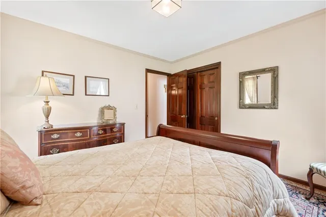 a bedroom with a bed table chair and a two windows