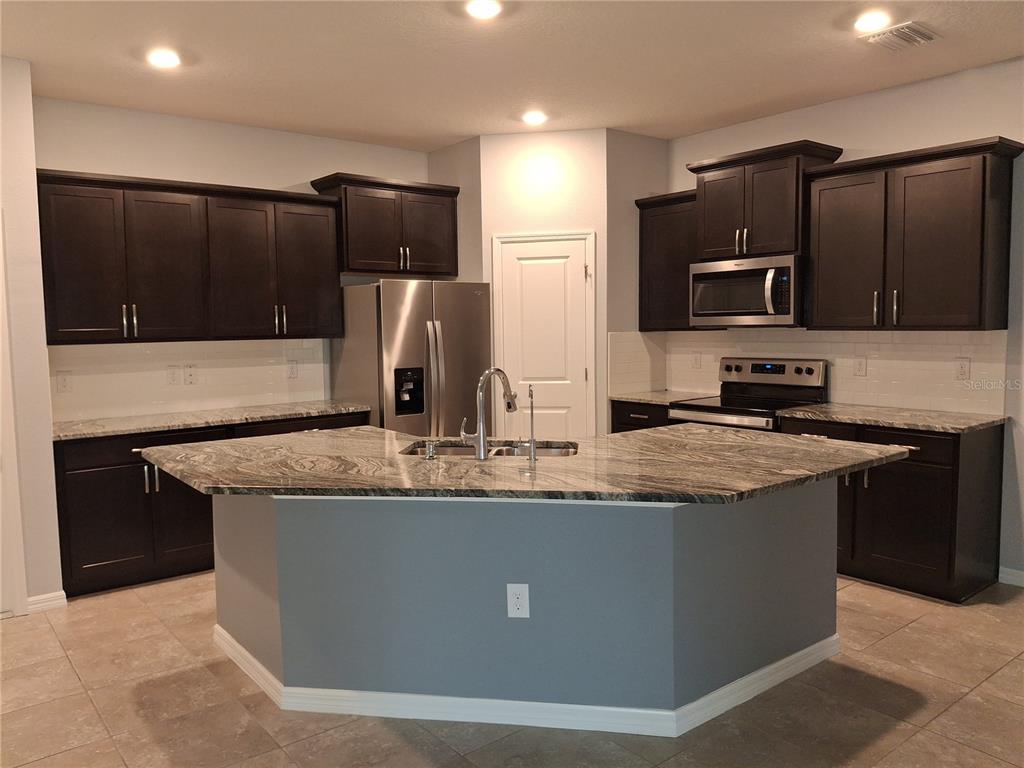 7891 Stonebrook Circle Wesley Chapel, FL 33545 - Photo 12 of 39 a kitchen with kitchen island granite countertop stainless steel appliances and cabinets