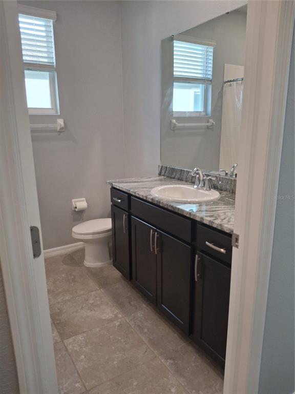 7891 Stonebrook Circle Wesley Chapel, FL 33545 - Photo 24 of 39 a bathroom with a granite countertop toilet a sink and a mirror