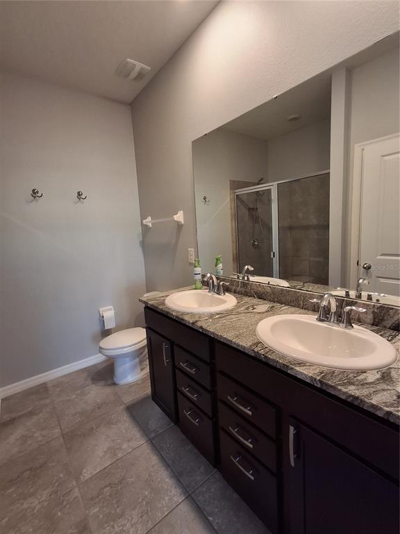7891 Stonebrook Circle Wesley Chapel, FL 33545 - Photo 32 of 39 a bathroom with a granite countertop sink a toilet and a mirror