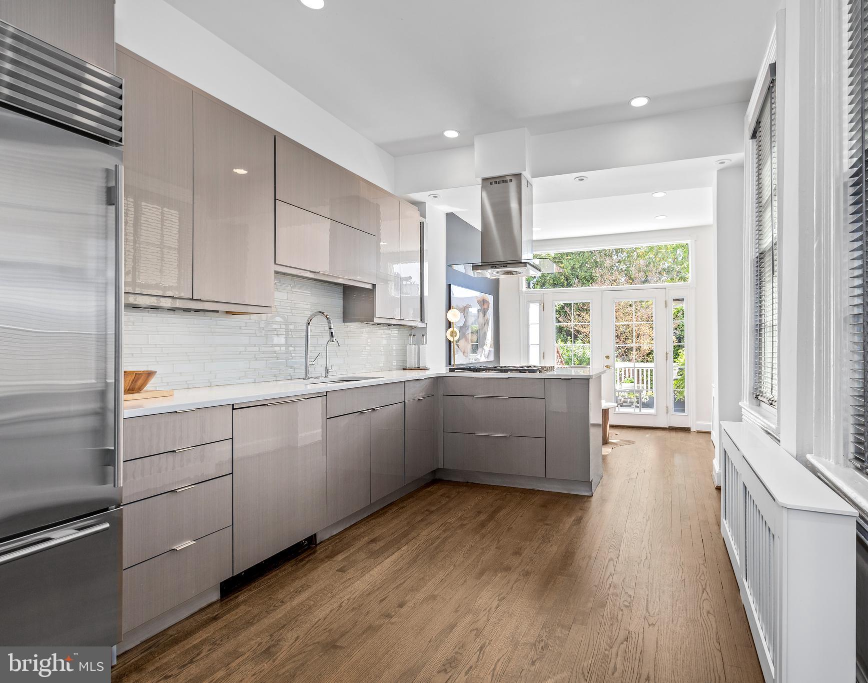 1213 29th Street Northwest Washington, DC 20007 - Photo 7 of 31 a kitchen with granite countertop a stove a sink and white cabinets with wooden floor