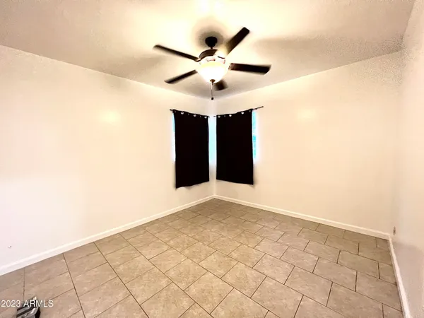 a view of an empty room with cabinet and a ceiling fan