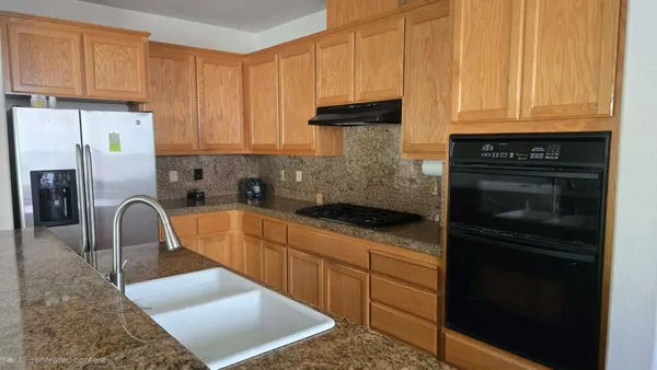 a kitchen with stainless steel appliances granite countertop a refrigerator sink and stove