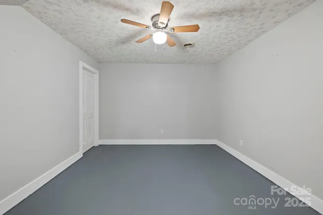 an empty room with a chandelier fan
